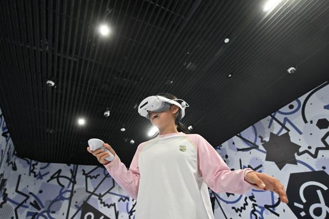 (261007) -- BEIJING, Oct. 7, 2026 (Xinhua) -- A child wearing VR glasses watches a video at Shangqiu Museum in Shangqiu, central China's Henan Province, Oct. 7, 2026. Advanced technologies such as exoskeleton devices, AI-powered glasses and robots have enabled diverse and dazzling experiences at tourist destinations across China during the National Day holiday. (Photo by Li Heng/Xinhua)