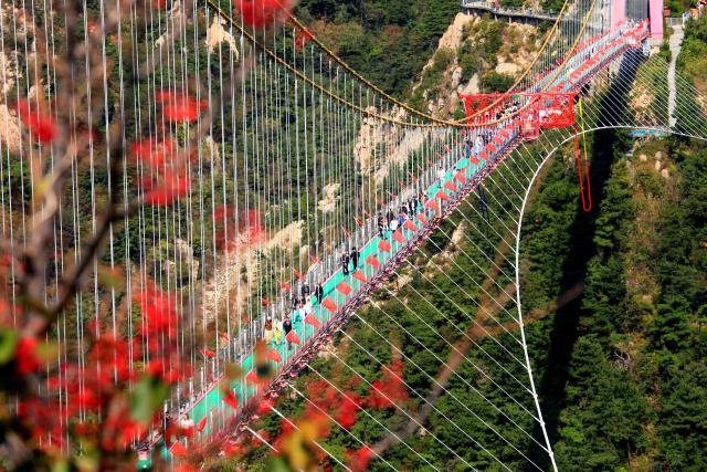 (261007) -- BEIJING, Oct. 7, 2026 (Xinhua) -- Tourists walk on a pedestrian suspension bridge in the Yimeng mountains in Linyi City, east China's Shandong Province, Oct. 7, 2026. People across the country enjoy themselves through various cultural and tourism activities and events during the National Day holiday. (Photo by Wu Jiquan/Xinhua)