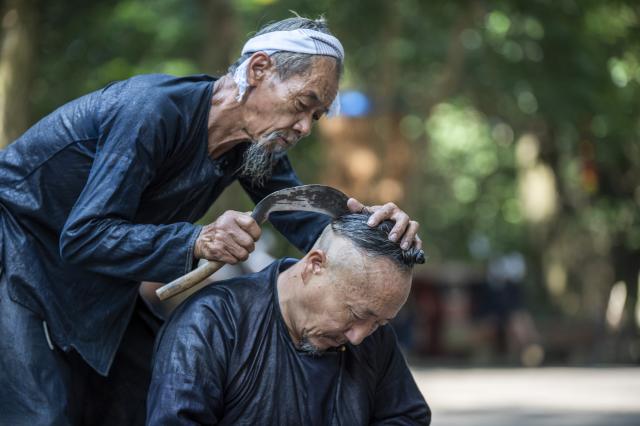 (261007) -- CONGJIANG, Oct. 7, 2026 (Xinhua) -- Villagers demonstrate sickle haircutting skill at Basha Village in Congjiang County of Qiandongnan Miao and Dong Autonomous Prefecture, southwest China's Guizhou Province, Aug. 20, 2026. Located seven kilometers away from the county seat of Congjiang, Basha Village has attracted an increasing number of overseas tourists with its charming scenery and simple folk customs recently. 
   Consisting of five hamlets and inhabited by the Miao people, the village was included in the first batch of China's traditional villages in 2012. Riding the viral "Chinamaxxing" wave on social media, foreign tourists have come here to experience ancient ways of life and profound cultural heritage. 
   Data from the National Immigration Administration shows that China recorded 22.91 million inbound foreign visits in the first half of this year, up 20.4 percent year on year. (Photo by Wu Dejun/Xinhua)