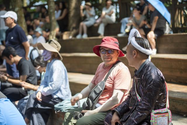 (261007) -- CONGJIANG, Oct. 7, 2026 (Xinhua) -- A foreign visitor chats with a villager at Basha Village in Congjiang County of Qiandongnan Miao and Dong Autonomous Prefecture, southwest China's Guizhou Province, Aug. 20, 2026. Located seven kilometers away from the county seat of Congjiang, Basha Village has attracted an increasing number of overseas tourists with its charming scenery and simple folk customs recently. 
   Consisting of five hamlets and inhabited by the Miao people, the village was included in the first batch of China's traditional villages in 2012. Riding the viral "Chinamaxxing" wave on social media, foreign tourists have come here to experience ancient ways of life and profound cultural heritage. 
   Data from the National Immigration Administration shows that China recorded 22.91 million inbound foreign visits in the first half of this year, up 20.4 percent year on year. (Photo by Wu Dejun/Xinhua)