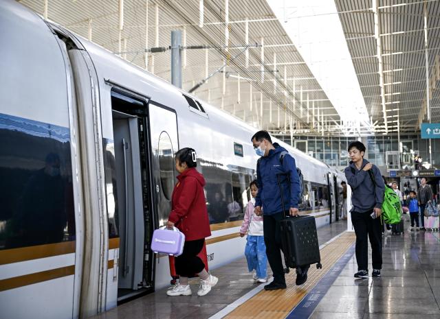 (261007) -- BEIJING, Oct. 7, 2026 (Xinhua) -- Passengers board a train at Hohhot East Railway Station in Hohhot, north China's Inner Mongolia Autonomous Region, Oct. 7, 2026. As the National Day holiday is drawing to a close, return travel flows increase across the country. (Xinhua/Li Zhipeng)
