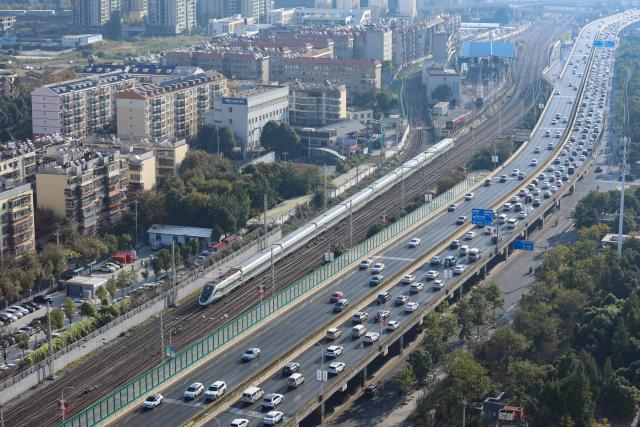 (261007) -- BEIJING, Oct. 7, 2026 (Xinhua) -- A bullet train runs in the urban area of Kunming, southwest China's Yunnan Province, Oct. 7, 2026. As the National Day holiday is drawing to a close, return travel flows increase across the country. (Photo by Zheng Yi/Xinhua)