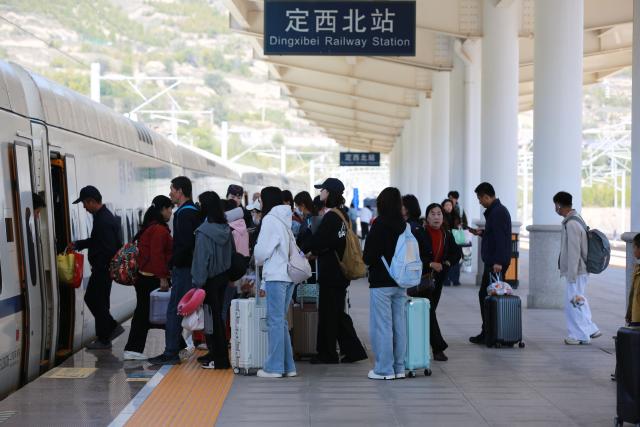 (261007) -- BEIJING, Oct. 7, 2026 (Xinhua) -- Passengers board a train at Dingxi North Railway Station in Dingxi City, northwest China's Gansu Province, Oct. 7, 2026. As the National Day holiday is drawing to a close, return travel flows increase across the country. (Photo by Wang Kexian/Xinhua)