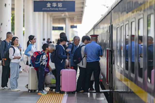 (261007) -- BEIJING, Oct. 7, 2026 (Xinhua) -- Passengers board a train at Jinhua Railway Station in Jinhua, east China's Zhejiang Province, Oct. 7, 2026. As the National Day holiday is drawing to a close, return travel flows increase across the country. (Photo by Hu Xiaofei/Xinhua)