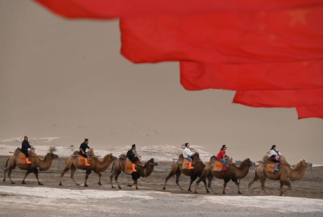 (261007) -- BEIJING, Oct. 7, 2026 (Xinhua) -- Tourists ride camels at the Mingsha Mountain and Crescent Spring Scenic Area in Dunhuang, northwest China's Gansu Province, Oct. 7, 2026. People across the country enjoy themselves through various cultural and tourism activities and events during the National Day holiday. (Photo by Zhang Xiaoliang/Xinhua)