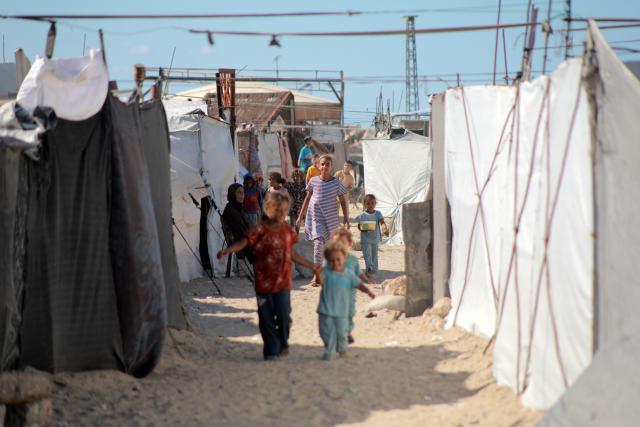 (261007) -- GAZA CITY, Oct. 7, 2026 (Xinhua) -- Children walk inside a makeshift tent camp in Gaza City, Oct. 7, 2026. The latest round of Gaza conflict marks its third anniversary on Wednesday. (Photo by Rizek Abdeljawad/Xinhua)