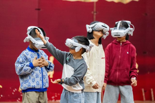 (261008) -- BEIJING, Oct. 8, 2026 (Xinhua) -- Children try on VR glasses at a science and technology museum in Bijie, southwest China's Guizhou Province, Oct. 6, 2026. Advanced technologies such as exoskeleton devices, AI-powered glasses and robots enabled diverse and dazzling experiences at tourist destinations across China during the National Day holiday. (Photo by Luo Dafu/Xinhua)