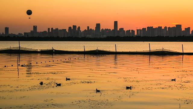 (261008) -- WUHAN, Oct. 8, 2026 (Xinhua) -- This photo taken with a mobile phone on Oct. 5, 2026 shows the East Lake at sunset in Wuhan, central China's Hubei Province. (Xinhua/Shen Hongbing)