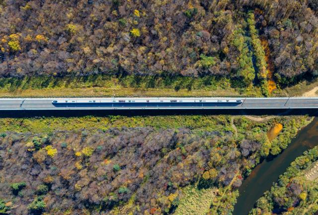 (261008) -- YICHUN, Oct. 8, 2026 (Xinhua) -- An aerial drone photo taken on Oct. 4, 2026 shows a bullet train of Harbin-Yichun high-speed railway running through forests in autumn scenery in Yichun, northeast China's Heilongjiang Province. The Harbin-Yichun high-speed railway, China's northernmost high-speed railway which officially entered service on Sept. 28, underlines the country's efforts to direct more transport infrastructure investment toward border areas, forest regions and less-developed regions, while helping boost development and prosperity in northeast China's border regions. (Photo by Li Jiaxing/Xinhua)