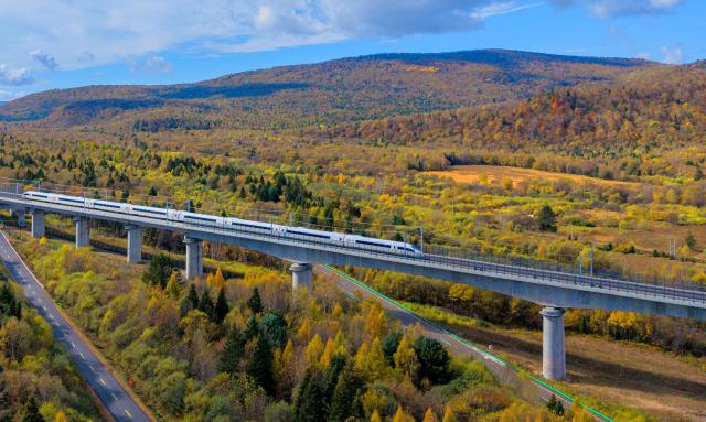(261008) -- YICHUN, Oct. 8, 2026 (Xinhua) -- An aerial drone photo taken on Sept. 30, 2026 shows a bullet train of Harbin-Yichun high-speed railway running through forests in autumn scenery in Yichun, northeast China's Heilongjiang Province. The Harbin-Yichun high-speed railway, China's northernmost high-speed railway which officially entered service on Sept. 28, underlines the country's efforts to direct more transport infrastructure investment toward border areas, forest regions and less-developed regions, while helping boost development and prosperity in northeast China's border regions. (Photo by Li Jiaxing/Xinhua)