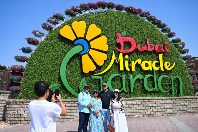 (261008) -- DUBAI, Oct. 8, 2026 (Xinhua) -- People pose for a group photo at Dubai Miracle Garden in Dubai, the United Arab Emirates, Oct. 8, 2026. Dubai Miracle Garden opened Thursday to the public for its 15th season. Featuring colorful floral displays and large-scale installations, the garden is a popular tourist attraction in Dubai. (Xinhua/Wang Zecong)