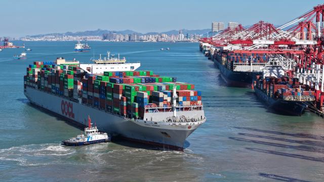 (261008) -- QINGDAO, Oct. 8, 2026 (Xinhua) -- A drone photo taken on Oct. 8, 2026 shows a cargo ship departing from Qingdao Port in Qingdao, east China's Shandong Province. As an international shipping hub in Northeast Asia, Qingdao Port has been expanding its shipping network, adding 16 foreign trade routes so far this year. The port now operates nearly 240 foreign trade routes, connecting over 700 ports in over 180 countries and regions. (Xinhua/Li Ziheng)