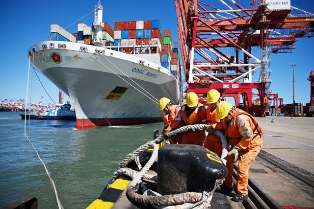 (261008) -- QINGDAO, Oct. 8, 2026 (Xinhua) -- Workers untie the mooring lines of a cargo ship at Qingdao Port in Qingdao, east China's Shandong Province, Oct. 8, 2026. As an international shipping hub in Northeast Asia, Qingdao Port has been expanding its shipping network, adding 16 foreign trade routes so far this year. The port now operates nearly 240 foreign trade routes, connecting over 700 ports in over 180 countries and regions. (Xinhua/Li Ziheng)