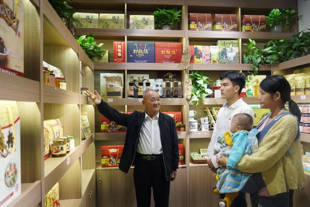 (261008) -- NANCHANG, Oct. 8, 2026 (Xinhua) -- This file photo taken on Oct. 21, 2020 shows Sun Guanfa (L) introducing local agricultural products to tourists in Tantou Village, Yudu County, east China's Jiangxi Province. (Xinhua/Wan Xiang)