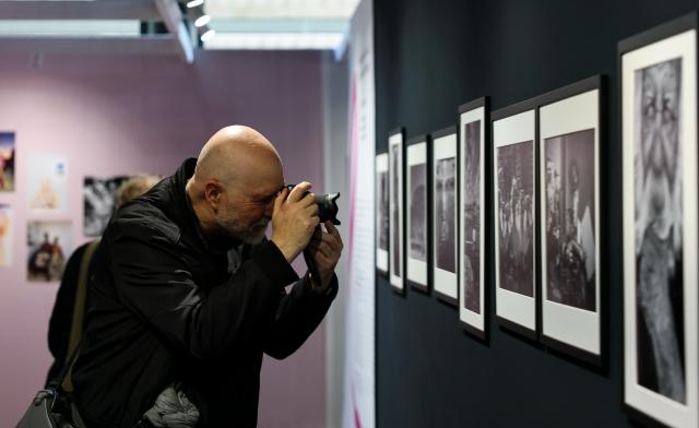 (261008) -- PARIS, Oct. 8, 2026 (Xinhua) -- A visitor takes photos during a photography exhibition at the Salon Photo & Video in Paris, France, Oct. 8, 2026. The Salon Photo & Video opened in Paris on Thursday, featuring equipment displays, photography exhibitions, talks and hands-on activities. (Xinhua/Wu Huiwo)