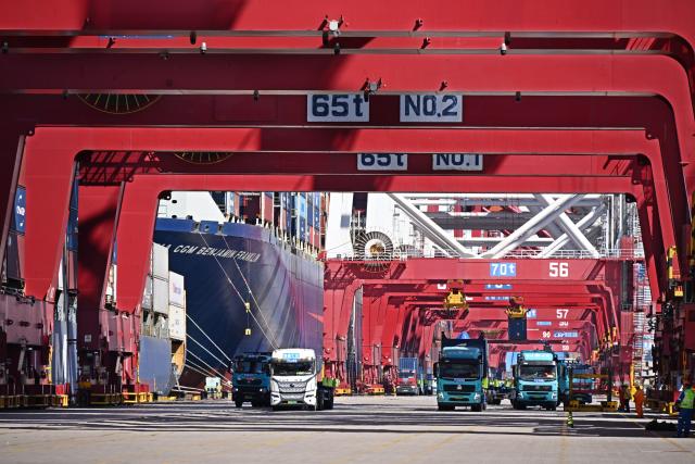 (261009) -- BEIJING, Oct. 9, 2026 (Xinhua) -- This photo taken on Oct. 8, 2026 shows freight trucks at a container terminal of Qingdao Port in Qingdao, east China's Shandong Province. As an international shipping hub in Northeast Asia, Qingdao Port has been expanding its shipping network, adding 16 foreign trade routes so far this year. The port now operates nearly 240 foreign trade routes, connecting over 700 ports in over 180 countries and regions. (Xinhua/Li Ziheng)