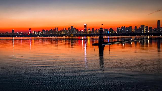 (261009) -- BEIJING, Oct. 9, 2026 (Xinhua) -- This photo taken with a mobile phone on Oct. 7, 2026 shows the East Lake at sunset in Wuhan, central China's Hubei Province. (Xinhua/Shen Hongbing)