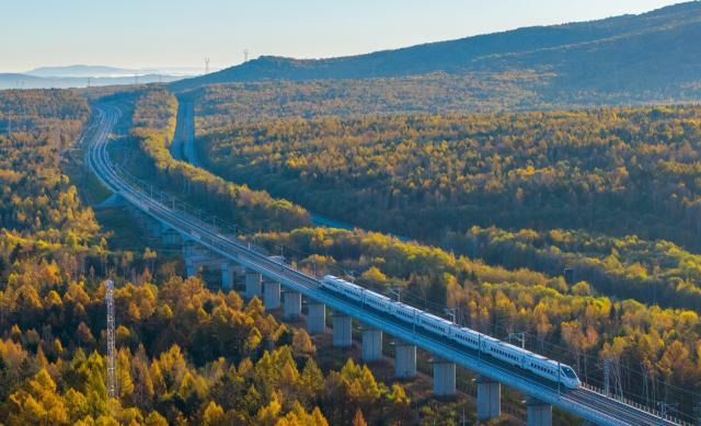(261009) -- BEIJING, Oct. 9, 2026 (Xinhua) -- An aerial drone photo taken on Oct. 4, 2026 shows a bullet train of Harbin-Yichun high-speed railway running through forests in autumn scenery in Yichun, northeast China's Heilongjiang Province. The Harbin-Yichun high-speed railway, China's northernmost high-speed railway which officially entered service on Sept. 28, underlines the country's efforts to direct more transport infrastructure investment toward border areas, forest regions and less-developed regions, while helping boost development and prosperity in northeast China's border regions. (Photo by Li Jiaxing/Xinhua)