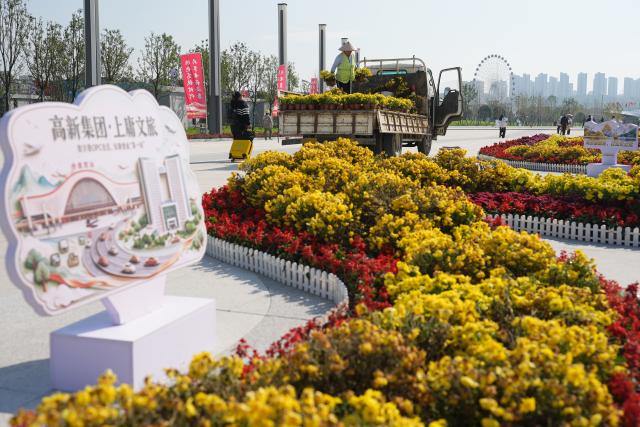 (261009) -- ANKANG, Oct. 9, 2026 (Xinhua) -- A worker places flowers outside the Ankang West Railway Station in Ankang, northwest China's Shaanxi Province, Oct. 8, 2026.
  The city of Ankang receives a surging number of tourists, thanks to the Xi'an-Ankang high-speed railway officially put into operation on Sept. 28 this year. The travel time between Xi'an, capital of Shaanxi, and Ankang has been slashed to less than one hour. (Xinhua/Shao Rui)