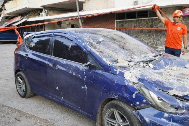 (261009) -- PENONOME(PANAMA), Oct. 9, 2026 (Xinhua) -- A rescuer stands beside a damaged vehicle after an earthquake in Penonome, central Cocle Province of Panama, Oct. 9, 2026. A major earthquake struck Panama on Friday. (Photo by Daniel Gonzalez/Xinhua)