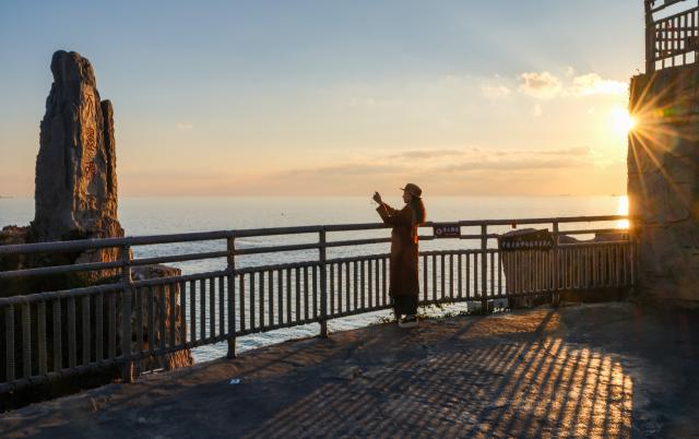 (261010) -- RONGCHENG, Oct. 10, 2026 (Xinhua) -- People capture sea views at sunrise in Rongcheng, east China's Shandong Province, Oct. 10, 2026. (Xinhua/Chen Yehua)