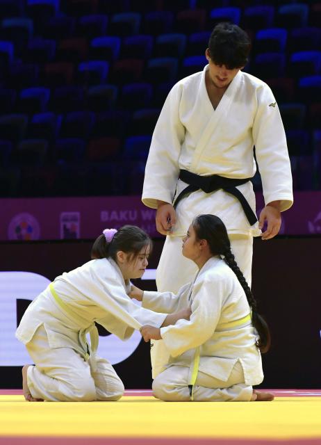 (261010) -- BAKU, Oct. 10, 2026 (Xinhua) -- Girls practice judo under the supervision on the official competition mat after the preliminary matches of the 2026 World Senior Judo Championships in Baku, Azerbaijan, Oct. 9, 2026. Azerbaijani judo coaches guide children with Down syndrome to experience judo. Under the supervision of elite athletes and coaches, the children learn basic techniques and judo etiquette on an official competition mat, embodying inclusive sport and judo's educational mission. (Xinhua/Chen Junfeng)