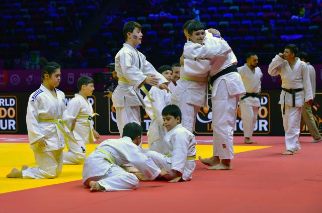 (261010) -- BAKU, Oct. 10, 2026 (Xinhua) -- Children experience judo on the official competition mat after the preliminary matches of the 2026 World Senior Judo Championships in Baku, Azerbaijan, Oct. 9, 2026. Azerbaijani judo coaches guide children with Down syndrome to experience judo. Under the supervision of elite athletes and coaches, the children learn basic techniques and judo etiquette on an official competition mat, embodying inclusive sport and judo's educational mission. (Xinhua/Chen Junfeng)