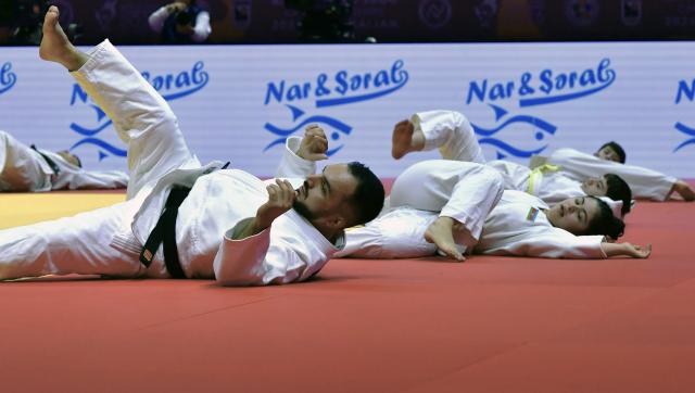 (261010) -- BAKU, Oct. 10, 2026 (Xinhua) -- Children practice judo with a coach on the official competition mat after the preliminary matches of the 2026 World Senior Judo Championships in Baku, Azerbaijan, Oct. 9, 2026. Azerbaijani judo coaches guide children with Down syndrome to experience judo. Under the supervision of elite athletes and coaches, the children learn basic techniques and judo etiquette on an official competition mat, embodying inclusive sport and judo's educational mission. (Xinhua/Chen Junfeng)