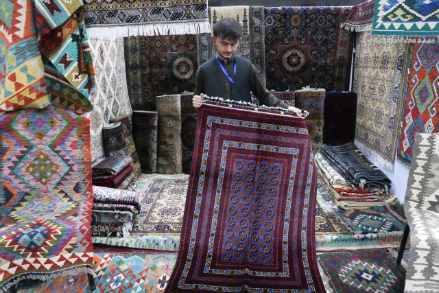 (261010) -- KABUL, Oct. 10, 2026 (Xinhua) -- An Afghan carpet trader showcases traditional Afghan carpets at a trade exhibition in Kabul, Afghanistan, Oct. 7, 2026. A major trade exhibition opened in Kabul, attracting hundreds of domestic and foreign investors to boost Afghanistan's trade ties with neighboring countries and unlock fresh opportunities for trade and investment. 
  TO GO WITH "Feature: Local trade exhibition bridges Afghan, int'l markets" (Photo by Saifurahman Safi/Xinhua)