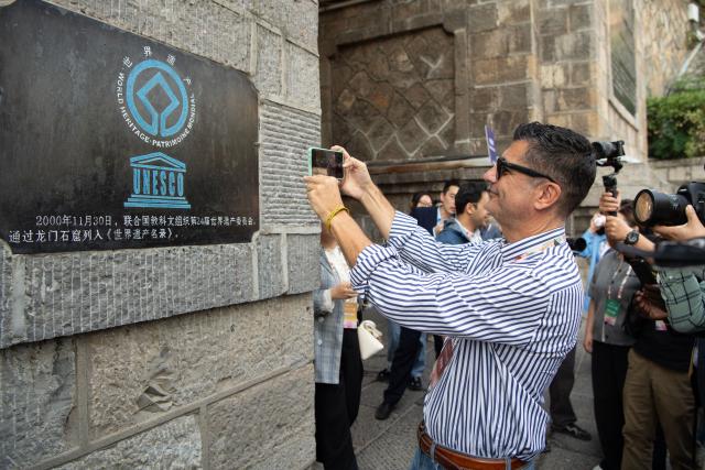 (261010) -- ZHENGZHOU, Oct. 10, 2026 (Xinhua) -- A guest visits the Longmen Grottoes scenic spot in Luoyang, central China's Henan Province, Oct. 10, 2026.
  From Oct. 9 to 10, guests from various countries attending the 2026 Global Mayors Dialogue in Luoyang visited a number of cultural landmarks and equipment manufacturing enterprises in Luoyang, experiencing the historical heritage and modern development of the ancient capital. (Photo by Kong Weijia/Xinhua)
