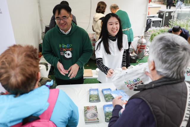 (261010) -- SIOFOK, Oct. 10, 2026 (Xinhua) -- Staff members introduce Chinese tourism to visitors during the 2026 Siofok Fish Festival in Siofok, Hungary, Oct. 10, 2026. Sit on the southern shore of Lake Balaton, Hungary's largest lake, Siofok is one of the country's leading lakeside holiday destinations. The city's annual fish festival is a major autumn event, with its 13th edition taking place on Oct. 9-11, 2026. (Xinhua/Hu Zhixuan)