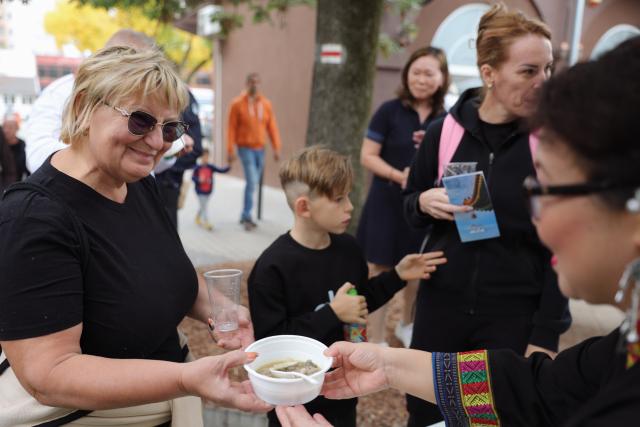 (261010) -- SIOFOK, Oct. 10, 2026 (Xinhua) -- A staff member serves a Chinese dish to a visitor during the 2026 Siofok Fish Festival in Siofok, Hungary, Oct. 10, 2026. Sit on the southern shore of Lake Balaton, Hungary's largest lake, Siofok is one of the country's leading lakeside holiday destinations. The city's annual fish festival is a major autumn event, with its 13th edition taking place on Oct. 9-11, 2026. (Xinhua/Hu Zhixuan)