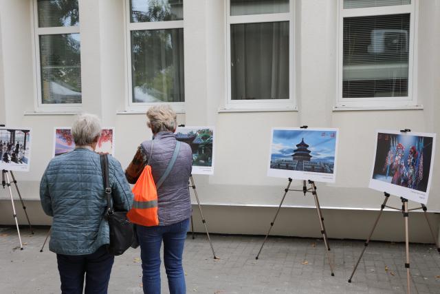 (261010) -- SIOFOK, Oct. 10, 2026 (Xinhua) -- People check a photo exhibition about China during the 2026 Siofok Fish Festival in Siofok, Hungary, Oct. 10, 2026. Sit on the southern shore of Lake Balaton, Hungary's largest lake, Siofok is one of the country's leading lakeside holiday destinations. The city's annual fish festival is a major autumn event, with its 13th edition taking place on Oct. 9-11, 2026. (Xinhua/Hu Zhixuan)