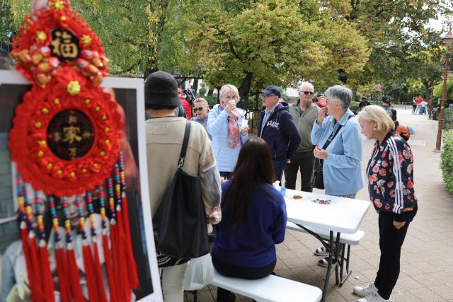(261010) -- SIOFOK, Oct. 10, 2026 (Xinhua) -- Visitors learn about Chinese food during the 2026 Siofok Fish Festival in Siofok, Hungary, Oct. 10, 2026. Sit on the southern shore of Lake Balaton, Hungary's largest lake, Siofok is one of the country's leading lakeside holiday destinations. The city's annual fish festival is a major autumn event, with its 13th edition taking place on Oct. 9-11, 2026. (Xinhua/Hu Zhixuan)