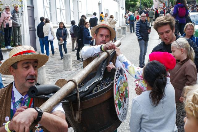 (261010) -- PARIS, Oct. 10, 2026 (Xinhua) -- Parade participants hand out grapes to spectators during the Montmartre Grape Harvest Festival in Paris, France, Oct. 10, 2026. The 93rd edition of the Montmartre Grape Harvest Festival runs from Oct. 7 to 11, featuring a grand parade, musical performances and other festivities. (Xinhua/Wu Huiwo)