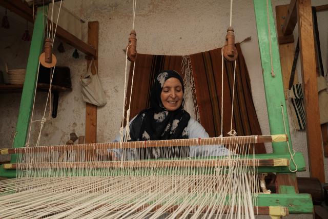 (261010) -- TRIPOLI, Oct. 10, 2026 (Xinhua) -- Aisha Madi weaves on a loom in a workshop in Tripoli, Libya, Sept. 29, 2026. TO GO WITH "Feature: Thread by thread, Libyan women keep an age-old craft alive" (Photo by Hazem Turkia/Xinhua)