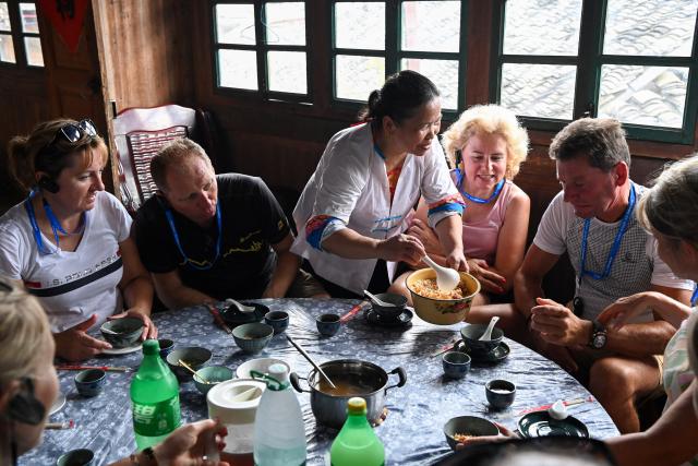 (261011) -- LONGSHENG, Oct. 11, 2026 (Xinhua) -- Foreign tourists enjoy Youcha, or oil tea, a kind of local delicacy, at Longji Village in Longsheng Ge Autonomous County, south China's Guangxi Zhuang Autonomous Region, Aug. 16, 2026.
  Longji Rice Terraces in Longji Village are a popular destination for visitors seeking to experience traditional Chinese rural life. The village, home mainly to the Zhuang ethnic group, features traditional wooden houses nestled among terraced fields and retains its distinctive ethnic cultural heritage.
  Drawing on its centuries-old rice-farming traditions, the village has integrated cultural heritage with tourism, offering activities such as mountain hiking, village tours, farming experiences and handicraft making. These activities have attracted lots of foreign visitors eager to experience the beauty of the landscape, traditional rice cultivation and ethnic culture in China. (Xinhua/Cao Yiming)