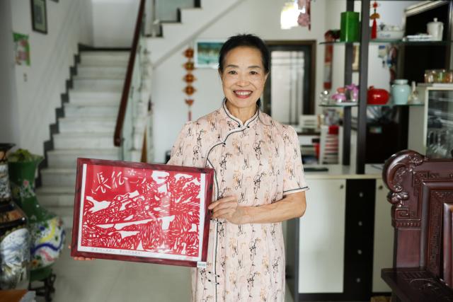(261012) -- NANCHANG, Oct. 12, 2026 (Xinhua) -- Liu Ying, a descendant of a Red Army soldier, also a member of the Long March Origin choir, displays her Long March-themed paper-cut work at home in Yudu County, east China's Jiangxi Province, Sept. 4, 2026. This year marks the 90th anniversary of the victory of the Long March. As one of its important starting points, Yudu County in east China's Jiangxi Province, a place best known as the starting point of the Long March by the Central Red Army, the historic military maneuver in modern Chinese history, has become more than a place of remembrance.
   It was from Yudu that more than 80,000 Red Army soldiers crossed the Yudu River and began the Long March in 1934, the roughly 12,500-kilometer trek later described by American journalist Harrison Salisbury as "a great human epic."
   On the stone tablet in front of the memorial museum of the Central Red Army's departure for the Long March here in Yudu, three Chinese characters meaning "Long March Origin" are engraved. The "Long March Origin" not only indicates that this place was the starting point of the important strategic transfer of the Red Army at that time, but also carries the profound understanding of the Long March spirit by the people of Yudu to this day.
   You can see the words "Long March Origin" frequently in Yudu, and the Long March Origin choir is a prominent presence.
   In this red revolutionary land of Yudu, almost everyone can share family stories connected to the Red Army's Long March. The Long March Origin choir, established in 2010, is composed of over 100 descendants of Red Army soldiers from all walks of life in the county. Over these years, they have not only performed the "Suite of Songs on the Long March" in Yudu and across Jiangxi in their spare time, but also carried forward the spirit of the Long March along the Long March route with their songs.
   The choir's first performance was staged on June 30, 2011, which was dedicated to the 90th anniversary of the founding of the Communist Party of China. So far the choir has performed over 730 charity performances. "We hope that the choir will complete 1,000 performances by the 100th anniversary of the victory of the Long March," said Zou Weimin, the director of the choir. (Xinhua/Wang Jingqiang)