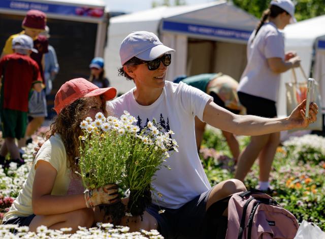(261012) -- CANBERRA, Oct. 12, 2026 (Xinhua) -- People take a selfie during the Great Big Bulb Dig event at Commonwealth Park in Canberra, Australia, on Oct. 12, 2026. The Great Big Bulb Dig, held annually following the end of the Floriade flower festival, attracted a large number of visitors to dig up and take home flower bulbs and annuals from the festival's display beds. (Photo by Chu Chen/Xinhua)