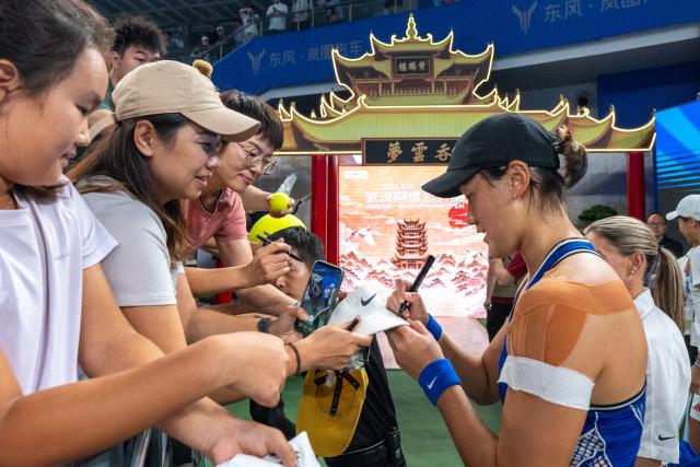 (261012) -- WUHAN, Oct. 12, 2026 (Xinhua) -- Wang Xiyu (R, front) signs autographs for fans after the women's sinlges round of 64 match between Wang Xiyu of China and Wang Xinyu of China of the 2026 Wuhan Open tennis tournament in Wuhan, capital of central China's Hubei Province, Oct. 12, 2026. (Xinhua/Xiao Yijiu)