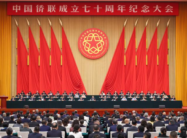 (261012) -- BEIJING, Oct. 12, 2026 (Xinhua) -- Wang Huning, a member of the Standing Committee of the Political Bureau of the Communist Party of China (CPC) Central Committee and chairman of the National Committee of the Chinese People's Political Consultative Conference (CPPCC), attends a conference marking the 70th anniversary of the establishment of the All-China Federation of Returned Overseas Chinese (ACFROC) and delivers a speech in Beijing, capital of China, Oct. 12, 2026. Wang met and posed for a group photo with representatives attending the conference. (Xinhua/Liu Bin)