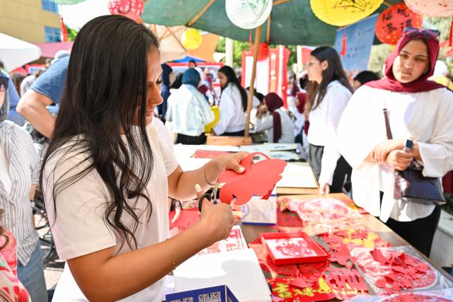 (261012) -- CAIRO, Oct. 12, 2026 (Xinhua) -- A visitor experiences paper-cutting during a Chinese culture festival at Badr University in Cairo, Egypt, Oct. 12, 2026. A Chinese culture festival was held Monday at Badr University in Cairo to celebrate the 70th anniversary of the establishment of diplomatic relations between China and Egypt, featuring cultural performances, traditional Chinese arts and student exchanges. (Xinhua/Xin Mengchen)