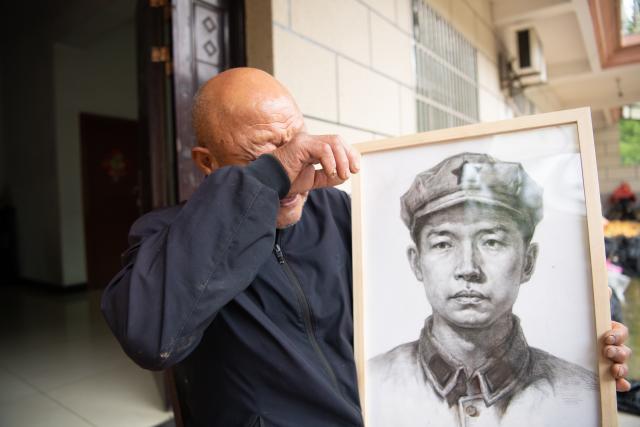 (261013) -- JINZHAI, Oct. 13, 2026 (Xinhua) -- Xu Shijia sheds tears when mentioning his grandfather Xu Qixin, a Red Army martyr who took part in the Long March, in Tangjiahui Town, Jinzhai County of east China's Anhui Province, Sept. 28, 2026. Members of the volunteer team drew the portrait of his grandfather. During this year's Mid-Autumn Festival holiday, a volunteer team from the Academy of Fine Arts of Anhui Normal University was busy in Jinzhai County of Lu'an City in east China's Anhui Province, drawing portraits of Red Army martyrs who participated in the Long March, the historic military maneuver in modern Chinese history, and presented them to the families of the martyrs.
   Since November 2021, the Academy of Fine Arts of Anhui Normal University has formed a team to carry out a series of volunteer services focused on drawing portraits of martyrs. Up to now, hundreds of students have participated in these activities, jointly drawing more than 600 portraits of martyrs, which have become an important way for their families to express feelings of longing.
   Across time and space, the youthful faces of those who had fallen on the battlefield were finally seen again by their families back home.
   Tucked in the Dabie Mountains, Jinzhai county contributed tens of thousands of people to the Communist Party of China (CPC)-led revolution in the first half of the 20th century. A total of 12 main units of the Red Army originated from here.
   Now, the Anhui Normal University project to paint portraits of Red Army martyrs is giving some families a long-awaited face to go with the stories passed down for generations. Usually the volunteer team would first contact the relatives of martyrs and then study photographs of the martyrs' descendants to determine basic facial contours. They would then revise the portraits repeatedly, drawing on family descriptions of the martyrs' eyes, expressions and habitual looks, until these relatives feel the likeness is right.
   For teachers and students of the team, painting portraits of martyrs is not merely a simple sketch creation but also an immersive study tour of revolutionary history. The brows and eyes rendered by the artists' brushes have captured the youthful appearance of the martyrs and also provided a place for the remembrance to rest. The past events recounted by the relatives of the martyrs are a testament to the enduring revolutionary legacy of the Dabie Mountains from generation to generation. (Xinhua/Zhang Duan)