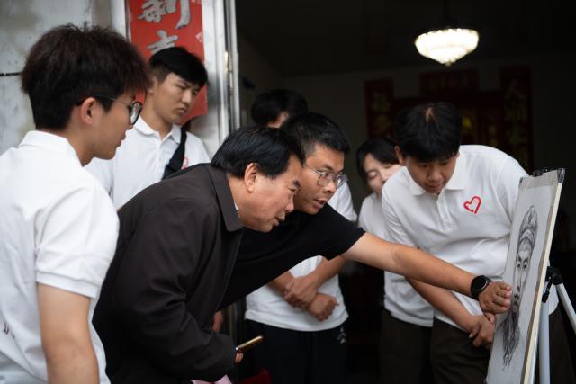 (261013) -- JINZHAI, Oct. 13, 2026 (Xinhua) -- Hu Xunxiu (3rd L), grandson of Red Army martyr Hu Jiufu, discusses details of the portrait of his grandfather with members of the volunteer team in Baojiyan Village of Tangjiahui Town, Jinzhai County of east China's Anhui Province, Sept. 26, 2026. During this year's Mid-Autumn Festival holiday, a volunteer team from the Academy of Fine Arts of Anhui Normal University was busy in Jinzhai County of Lu'an City in east China's Anhui Province, drawing portraits of Red Army martyrs who participated in the Long March, the historic military maneuver in modern Chinese history, and presented them to the families of the martyrs.
   Since November 2021, the Academy of Fine Arts of Anhui Normal University has formed a team to carry out a series of volunteer services focused on drawing portraits of martyrs. Up to now, hundreds of students have participated in these activities, jointly drawing more than 600 portraits of martyrs, which have become an important way for their families to express feelings of longing.
   Across time and space, the youthful faces of those who had fallen on the battlefield were finally seen again by their families back home.
   Tucked in the Dabie Mountains, Jinzhai county contributed tens of thousands of people to the Communist Party of China (CPC)-led revolution in the first half of the 20th century. A total of 12 main units of the Red Army originated from here.
   Now, the Anhui Normal University project to paint portraits of Red Army martyrs is giving some families a long-awaited face to go with the stories passed down for generations. Usually the volunteer team would first contact the relatives of martyrs and then study photographs of the martyrs' descendants to determine basic facial contours. They would then revise the portraits repeatedly, drawing on family descriptions of the martyrs' eyes, expressions and habitual looks, until these relatives feel the likeness is right.
   For teachers and students of the team, painting portraits of martyrs is not merely a simple sketch creation but also an immersive study tour of revolutionary history. The brows and eyes rendered by the artists' brushes have captured the youthful appearance of the martyrs and also provided a place for the remembrance to rest. The past events recounted by the relatives of the martyrs are a testament to the enduring revolutionary legacy of the Dabie Mountains from generation to generation. (Xinhua/Zhang Duan)