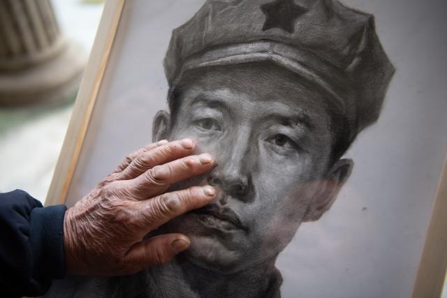 (261013) -- JINZHAI, Oct. 13, 2026 (Xinhua) -- Xu Shijia touches the portrait of his grandfather Xu Qixin, a Red Army martyr who took part in the Long March, in Tangjiahui Town, Jinzhai County of east China's Anhui Province, Sept. 28, 2026. During this year's Mid-Autumn Festival holiday, a volunteer team from the Academy of Fine Arts of Anhui Normal University was busy in Jinzhai County of Lu'an City in east China's Anhui Province, drawing portraits of Red Army martyrs who participated in the Long March, the historic military maneuver in modern Chinese history, and presented them to the families of the martyrs.
   Since November 2021, the Academy of Fine Arts of Anhui Normal University has formed a team to carry out a series of volunteer services focused on drawing portraits of martyrs. Up to now, hundreds of students have participated in these activities, jointly drawing more than 600 portraits of martyrs, which have become an important way for their families to express feelings of longing.
   Across time and space, the youthful faces of those who had fallen on the battlefield were finally seen again by their families back home.
   Tucked in the Dabie Mountains, Jinzhai county contributed tens of thousands of people to the Communist Party of China (CPC)-led revolution in the first half of the 20th century. A total of 12 main units of the Red Army originated from here.
   Now, the Anhui Normal University project to paint portraits of Red Army martyrs is giving some families a long-awaited face to go with the stories passed down for generations. Usually the volunteer team would first contact the relatives of martyrs and then study photographs of the martyrs' descendants to determine basic facial contours. They would then revise the portraits repeatedly, drawing on family descriptions of the martyrs' eyes, expressions and habitual looks, until these relatives feel the likeness is right.
   For teachers and students of the team, painting portraits of martyrs is not merely a simple sketch creation but also an immersive study tour of revolutionary history. The brows and eyes rendered by the artists' brushes have captured the youthful appearance of the martyrs and also provided a place for the remembrance to rest. The past events recounted by the relatives of the martyrs are a testament to the enduring revolutionary legacy of the Dabie Mountains from generation to generation. (Xinhua/Zhang Duan)