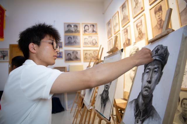 (261013) -- JINZHAI, Oct. 13, 2026 (Xinhua) -- Wang Chenhuan creates a portrait of Xu Qixin, a Red Army martyr who took part in the Long March, at Anhui Normal University in Wuhu, east China's Anhui Province, Sept. 25, 2026. During this year's Mid-Autumn Festival holiday, a volunteer team from the Academy of Fine Arts of Anhui Normal University was busy in Jinzhai County of Lu'an City in east China's Anhui Province, drawing portraits of Red Army martyrs who participated in the Long March, the historic military maneuver in modern Chinese history, and presented them to the families of the martyrs.
   Since November 2021, the Academy of Fine Arts of Anhui Normal University has formed a team to carry out a series of volunteer services focused on drawing portraits of martyrs. Up to now, hundreds of students have participated in these activities, jointly drawing more than 600 portraits of martyrs, which have become an important way for their families to express feelings of longing.
   Across time and space, the youthful faces of those who had fallen on the battlefield were finally seen again by their families back home.
   Tucked in the Dabie Mountains, Jinzhai county contributed tens of thousands of people to the Communist Party of China (CPC)-led revolution in the first half of the 20th century. A total of 12 main units of the Red Army originated from here.
   Now, the Anhui Normal University project to paint portraits of Red Army martyrs is giving some families a long-awaited face to go with the stories passed down for generations. Usually the volunteer team would first contact the relatives of martyrs and then study photographs of the martyrs' descendants to determine basic facial contours. They would then revise the portraits repeatedly, drawing on family descriptions of the martyrs' eyes, expressions and habitual looks, until these relatives feel the likeness is right.
   For teachers and students of the team, painting portraits of martyrs is not merely a simple sketch creation but also an immersive study tour of revolutionary history. The brows and eyes rendered by the artists' brushes have captured the youthful appearance of the martyrs and also provided a place for the remembrance to rest. The past events recounted by the relatives of the martyrs are a testament to the enduring revolutionary legacy of the Dabie Mountains from generation to generation. (Xinhua/Zhang Duan)