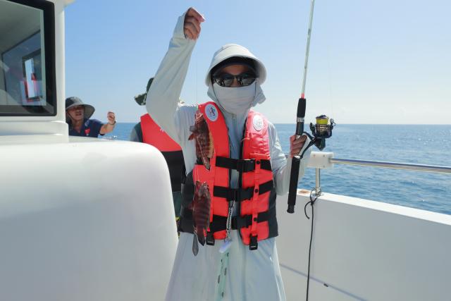 (261013) -- HAIKOU, Oct. 13, 2026 (Xinhua) -- A tourist displays fish on a recreational fishing boat in Tanmen Town of Qionghai, south China's Hainan Province, Oct. 1, 2026. TO GO WITH "Across China: Fishing tourism on the rise in historic south China port" (Xinhua)