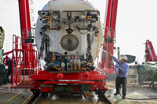 (261013) -- ABOARD RESEARCH VESSEL DEEP SEA NO. 1, Oct. 13, 2026 (Xinhua) -- Staff members clean the manned deep-sea submersible Jiaolong after its dive aboard the research vessel Deep Sea No. 1, on Oct. 11, 2026. China's manned deep-sea submersible Jiaolong successfully completed its 467th dive. The dive reached a depth of approximately 4,400 meters. (Xinhua/Li Xin)