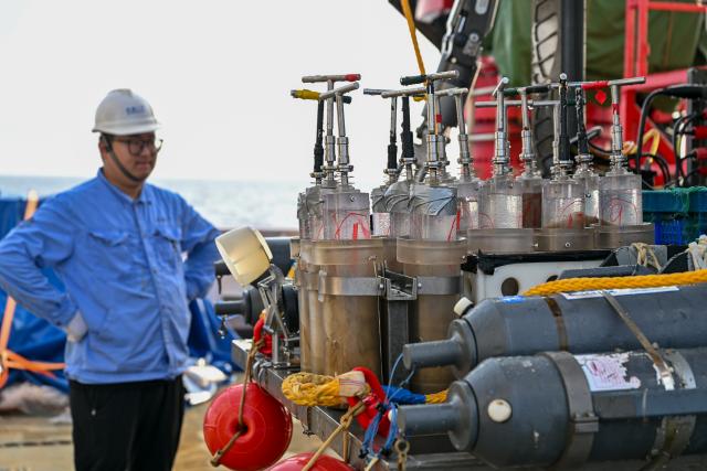 (261013) -- ABOARD RESEARCH VESSEL DEEP SEA NO. 1, Oct. 13, 2026 (Xinhua) -- A staff member looks at deep-sea samples collected by the manned deep-sea submersible Jiaolong aboard the research vessel Deep Sea No. 1, on Oct. 11, 2026. China's manned deep-sea submersible Jiaolong successfully completed its 467th dive. The dive reached a depth of approximately 4,400 meters. (Xinhua/Ye Haoming)