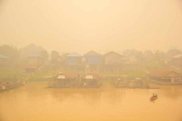 (261013) -- PALANGKA RAYA, Oct. 13, 2026 (Xinhua) -- People take a boat amid thick haze caused by forest and peatland fires in Palangka Raya, Central Kalimantan, Indonesia, Oct. 12, 2026. (Photo by Dirga Gendes/Xinhua)